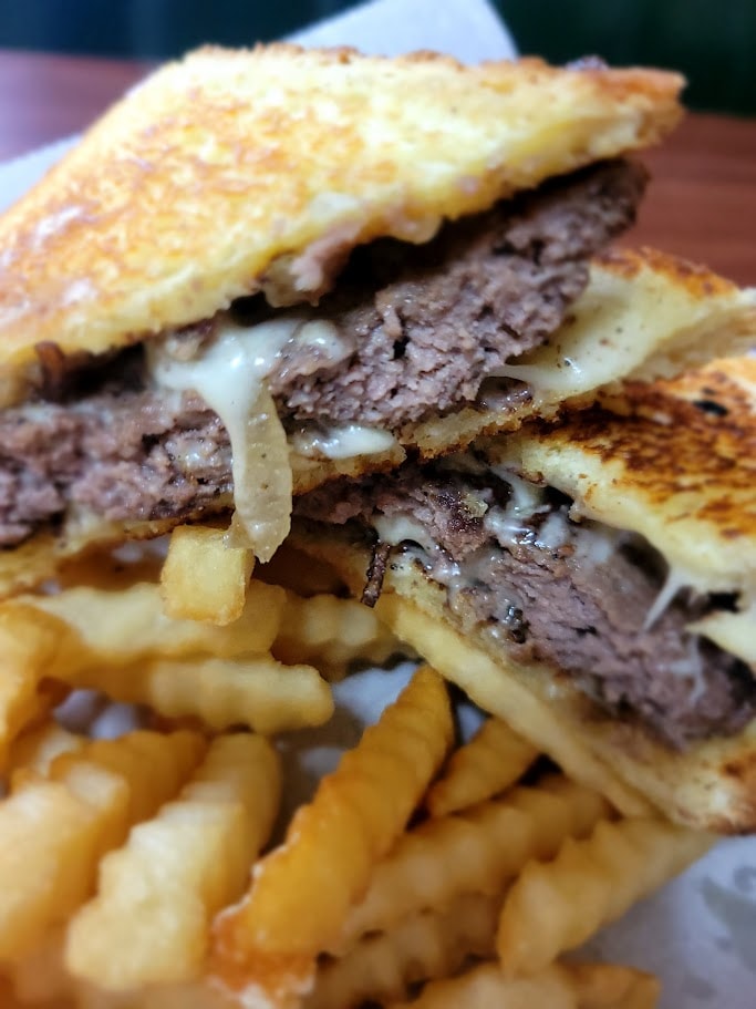 Stacked beef sandwich with melted cheese and fries